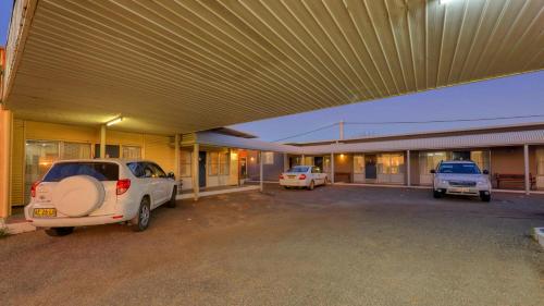 two cars parked in a parking lot in front of a building at Silver Haven Motor Inn in Broken Hill