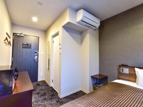 a hotel room with a bed and a tv at HOTEL LiVEMAX Fukuoka Tenjin West in Fukuoka