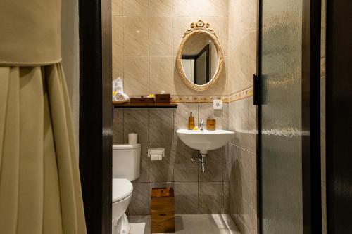 a bathroom with a toilet and a sink and a mirror at Tigata Ubud Cottage in Ubud