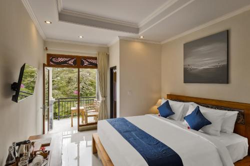 a bedroom with a large bed and a balcony at Tigata Ubud Cottage in Ubud