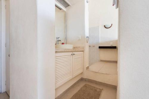 uma casa de banho branca com um lavatório e um espelho em Hermosa Villa Puesta al SOL em Acapulco