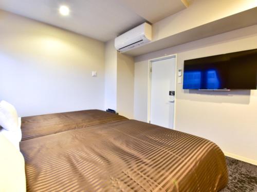 a bedroom with a bed and a flat screen tv at HOTEL LiVEMAX Fukuoka Tenjin West in Fukuoka