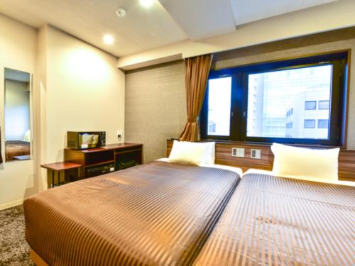 a bedroom with two beds and a large window at HOTEL LiVEMAX Fukuoka Tenjin West in Fukuoka