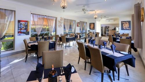 a restaurant with tables and chairs and bottles of wine at Silver Haven Motor Inn in Broken Hill