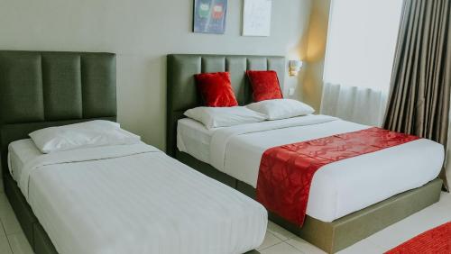two beds with red pillows in a hotel room at Destini Akef Villa in Pantai Cenang