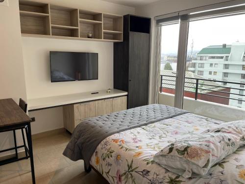 a bedroom with a bed and a tv and a window at Departamento Centro de Valdivia, Caupolican in Valdivia