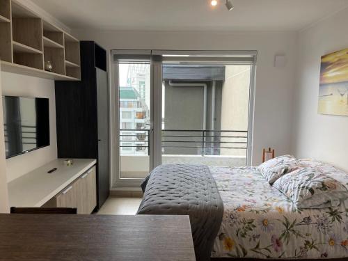 a bedroom with a bed and a view of a balcony at Departamento Centro de Valdivia, Caupolican in Valdivia