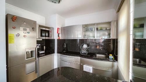 a kitchen with white cabinets and a black counter top at Reis Magos Beach Caniço Sea line Apartment in Caniço