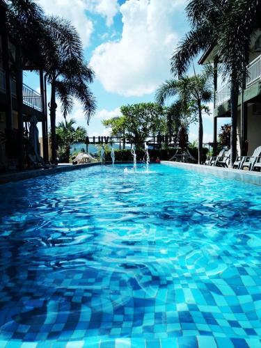 a large swimming pool with blue water and palm trees at Destini Akef Villa in Pantai Cenang