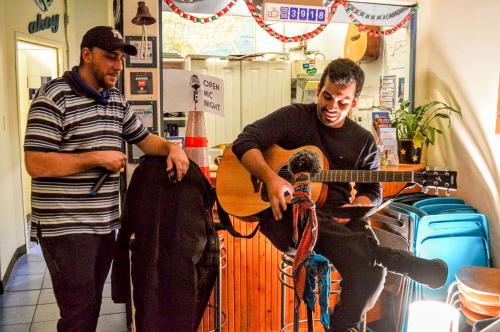 a man playing a guitar while another man plays a guitar at ITH San Francisco Pacific Tradewinds Backpacker Hostel in San Francisco