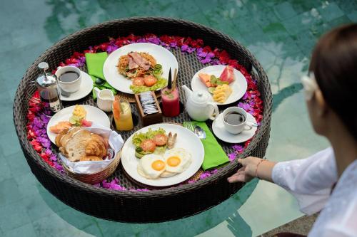 een vrouw die voor een tafel met eten staat bij Tigata Ubud Cottage in Ubud