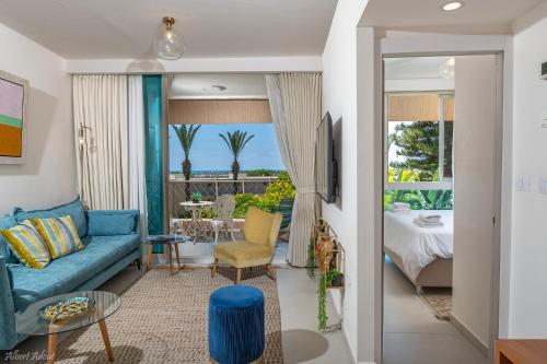 凱撒利亞的住宿－Mina's Suites - קיסריה，一间带蓝色沙发的客厅和一个阳台