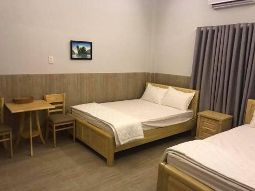 a room with two beds and a table and a table and a bed at NHÀ KHÁCH HOA SEN in Kinh Dinh