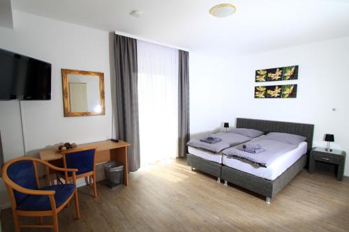 a bedroom with a bed and a desk and a television at Hotel Sonnenhof in Sindelfingen