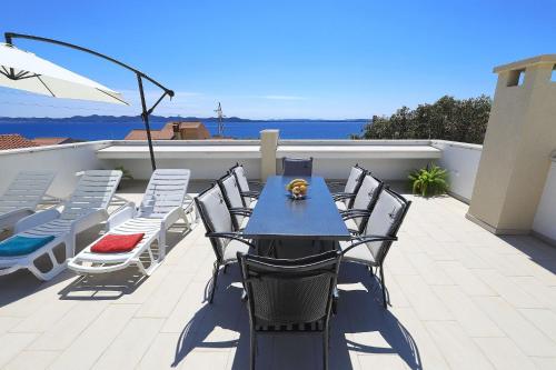 een blauwe tafel en stoelen op een patio met uitzicht op de oceaan bij Vidalis, no 1 in Kožino