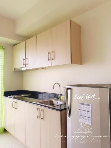 a kitchen with white cabinets and a stainless steel refrigerator at Leaf Taal View No Balcony in Tagaytay