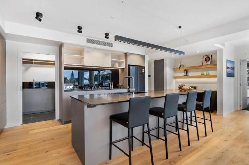 a kitchen with a island with bar stools at The Essence of Queenstown in Queenstown