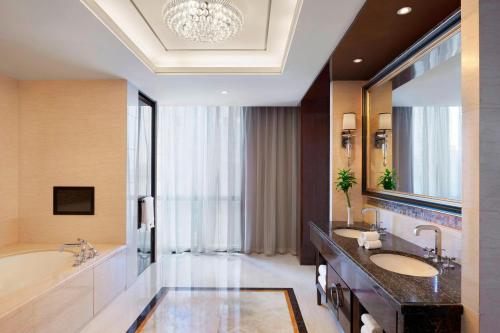 La salle de bains est pourvue de 2 lavabos, d'une baignoire et d'un grand miroir. dans l'établissement The Westin Wuhan Wuchang, à Wuhan