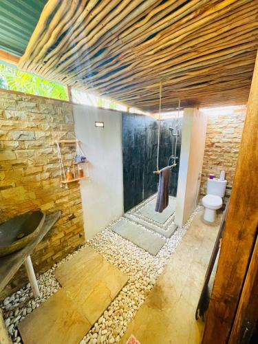 La salle de bains est pourvue de toilettes et d'un mur en pierre. dans l'établissement SAJA Cottage, Gili Meno, à Gili Meno