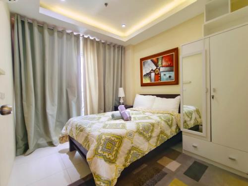 a bedroom with a bed and a window at Mackenzie Penthouse Taal View with balcony in Tagaytay