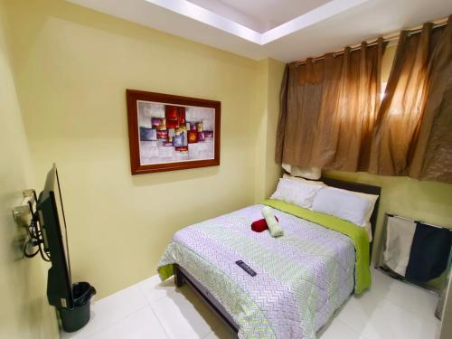 a small bedroom with a bed and a tv at Mackenzie Penthouse Taal View with balcony in Tagaytay