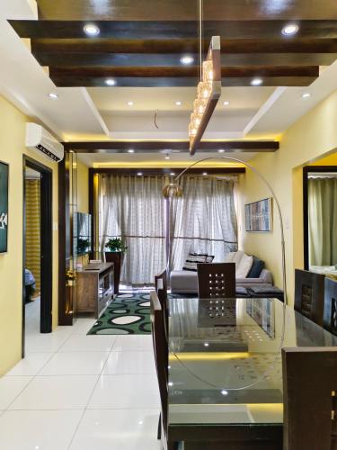 a dining room with a glass table and a couch at Mackenzie Penthouse Taal View with balcony in Tagaytay
