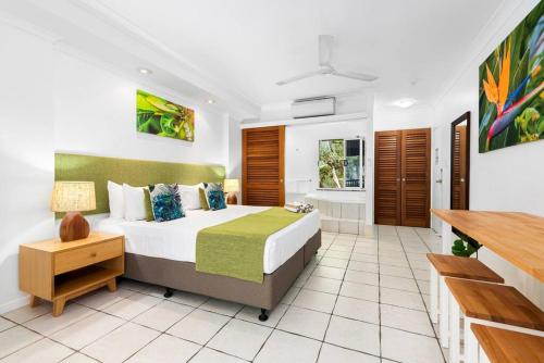 Palm Cove Treetop Spa Retreat في بالم كوف: غرفة نوم بسرير كبير وحوض استحمام