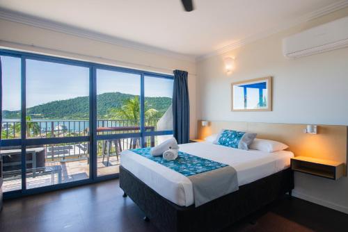 1 dormitorio con 1 cama grande y balcón en Coral Sea Vista Apartments en Airlie Beach