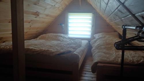 a bedroom with two beds and a window at Domki Tomek Bieszczady 509-000-966 in Polańczyk