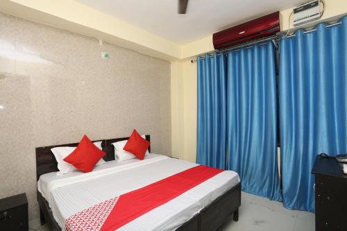 a bedroom with a bed with red pillows and blue curtains at Flagship Hotel Dream Connect in Ghaziabad