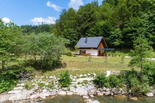 una pequeña cabaña en el bosque al lado de un río en Riverside Resort Stari Malni Kolpa - Happy Rentals, en Osilnica