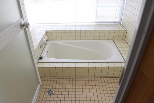 a white tub in a tiled bathroom with a window at コテージ　マリーゴールド in Nasu-yumoto