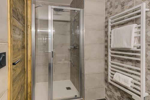 La salle de bains est pourvue d'une douche avec une porte en verre. dans l'établissement White Pearl A05 Modern apartment Chamonix Alpes Travel Sleeps 4 to 6, à Chamonix-Mont-Blanc