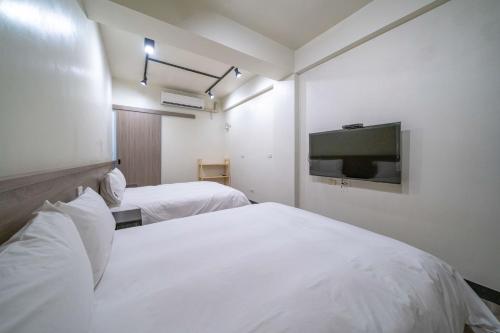 um quarto de hotel com duas camas e uma televisão de ecrã plano em 安平-宅17包棟民宿 x 户外烤肉區-依人數開放房型 em Anping