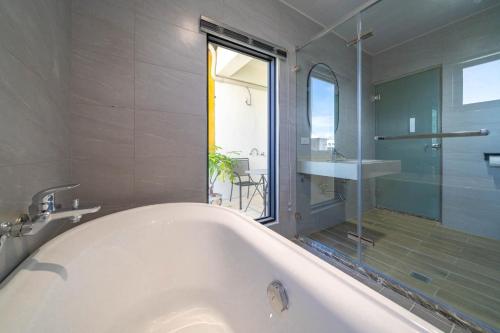 uma banheira branca na casa de banho com uma janela em 安平-宅17包棟民宿 x 户外烤肉區-依人數開放房型 em Anping