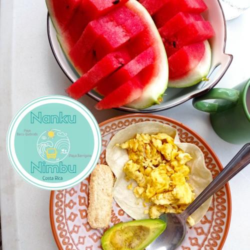 a plate of food with watermelon and a plate of cornbread at Nanku Nimbu Casa-Bus equipada cerca de playas in Sámara