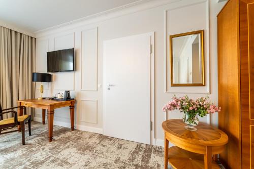 a hotel room with a desk and a table with flowers at Hotel Piast in Opole