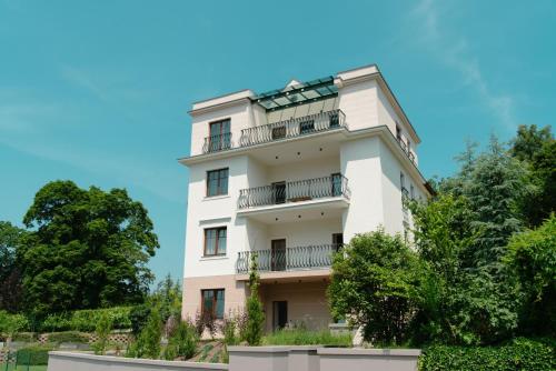 ein weißes Gebäude mit Balkonen und Bäumen in der Unterkunft Vila Maister in Celje