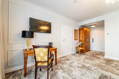a room with a desk and a table with a chair at Hotel Piast in Opole