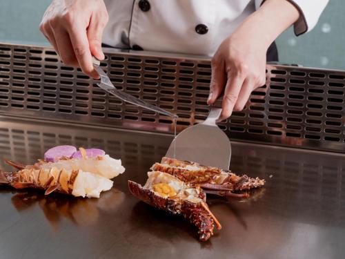 a person cutting up food on a counter with spatulas at Windsor Hotel Taichung in Taichung
