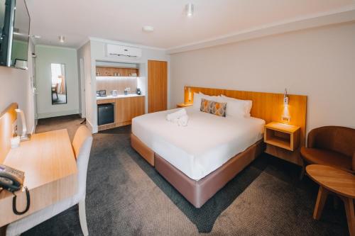 a hotel room with a large bed and a kitchen at Clarion Hotel Townsville in Townsville