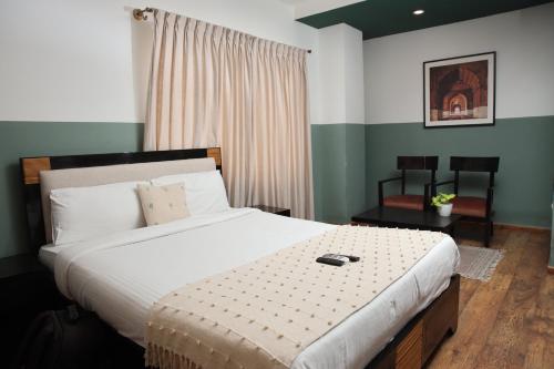 a bedroom with a large bed and a chair at Olive Zip Rest House Road by Embassy Group in Bengaluru