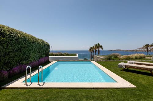 a swimming pool in the grass with a view of the ocean at Santa Marina, A Luxury Collection Resort, Mykonos in Ornos