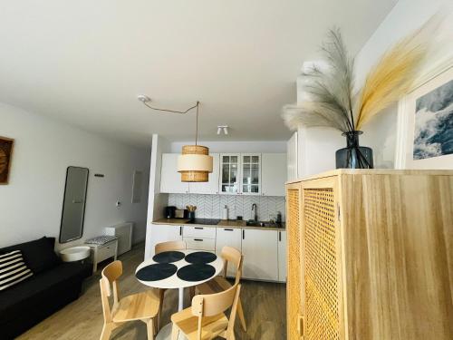 Il comprend une cuisine et un salon avec une table et des chaises. dans l'établissement Łebska Ostoja Piaskowa Apartament 2-2, à Żarnowska