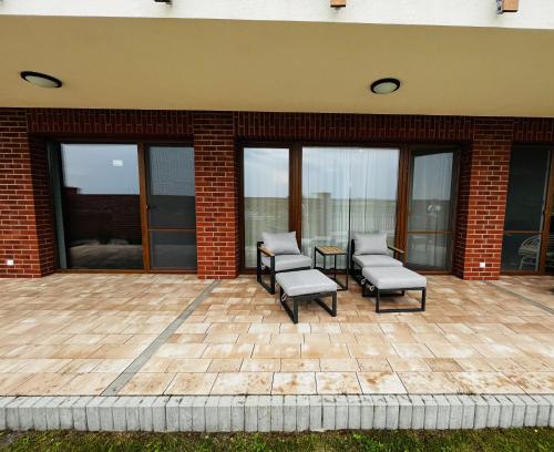 a patio with two chairs and a table and windows at Łebska Ostoja Piaskowa Apartament 2-2 in Żarnowska