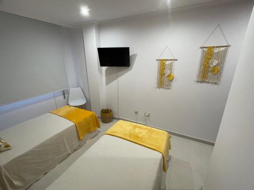 een kleine witte kamer met een bed en een televisie bij Apartamentos Demar Luis Casais in O Grove