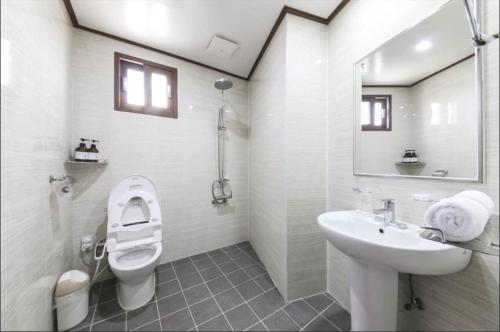 a white bathroom with a toilet and a sink at The Seri Resort in Seogwipo