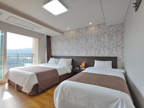 a bedroom with two beds and a large window at Jeju Lavender Hotel in Seogwipo