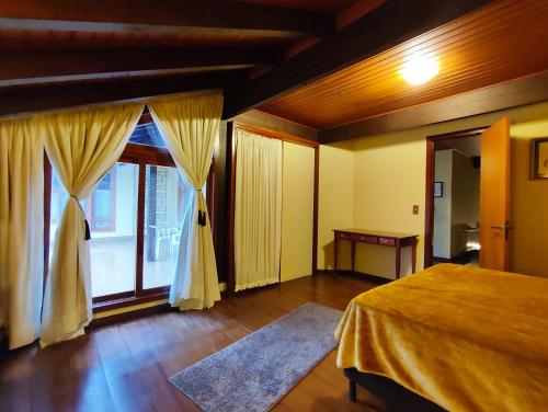 1 dormitorio con cama y ventana grande en Mais Incrível Apart no Wish Serrano, en Gramado