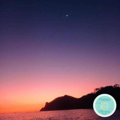 a sunset over the ocean with the moon in the sky at Nanku Nimbu Casa-Bus equipada cerca de playas in Sámara
